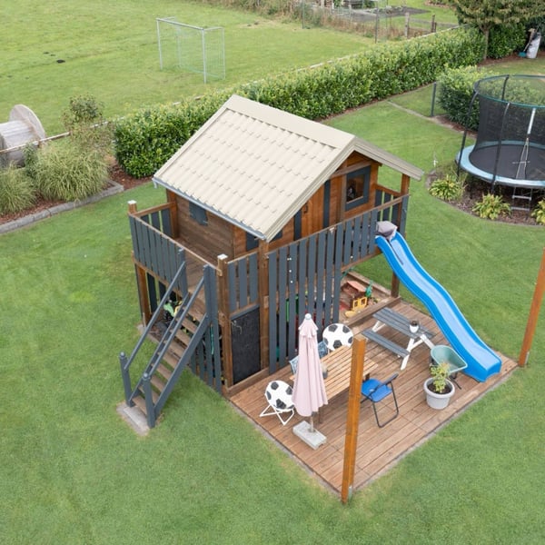 Speelhuis met dak van dakpanplaat 2/1060 Zuiverwit (RAL 9010) en glijbaan in de tuin