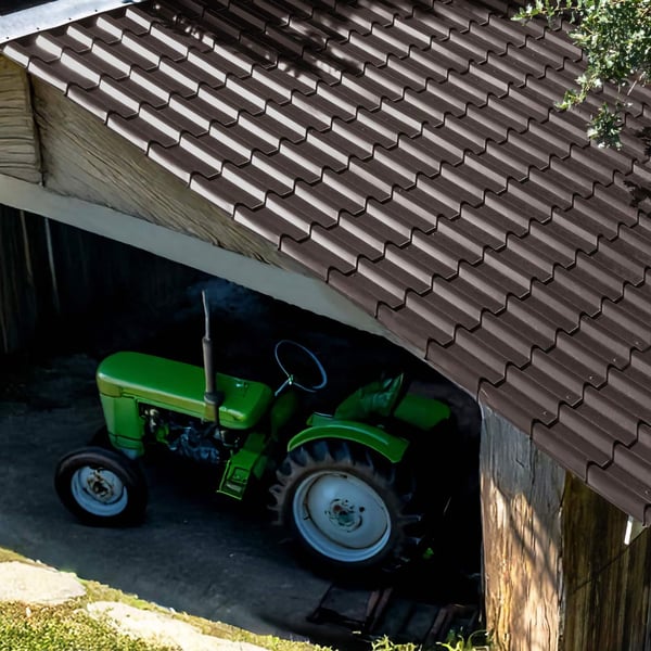 Dakpanplaat EUROPA sepiabruin op een schuurdak, eronder een groene tractor