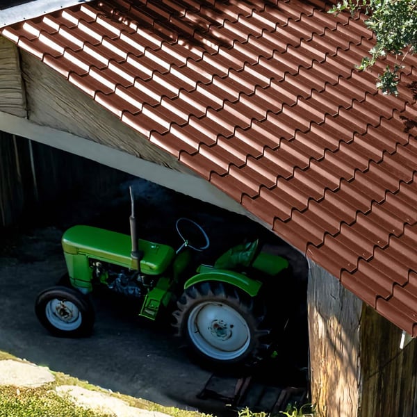 Roodbruine dakpanplaat EUROPA op een schuurdak, daaronder een groene tractor