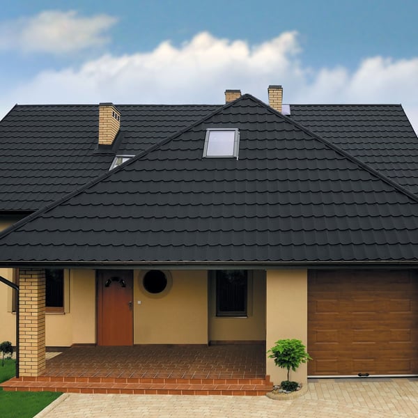 Dak van een huis met antracietgrijze dakpanplaat Szafir 350/15, vooraanzicht met dakkapel en schoorstenen