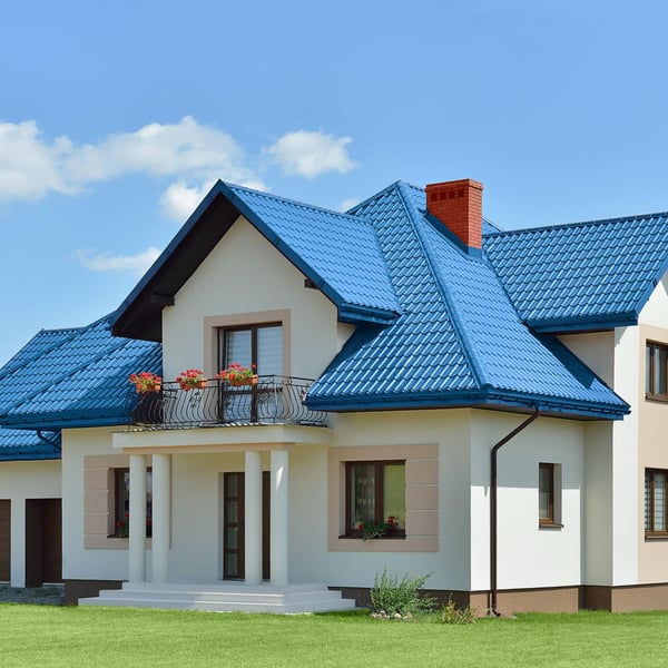 Huis met dak van dakpanplaat Szafir 350/15 in Gentiaanblauw, met balkon en witte gevel