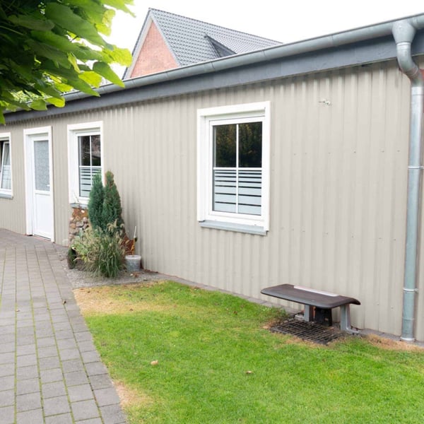 Zijaanzicht van een gebouw met damwandplaat 20/1100 Grijswit (RAL 9002) aan de wand