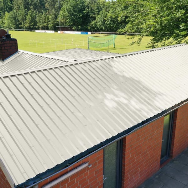 Damwandplaat 35/207 dak, Grijswit, gemonteerd op een lang gebouw met rode bakstenen gevel