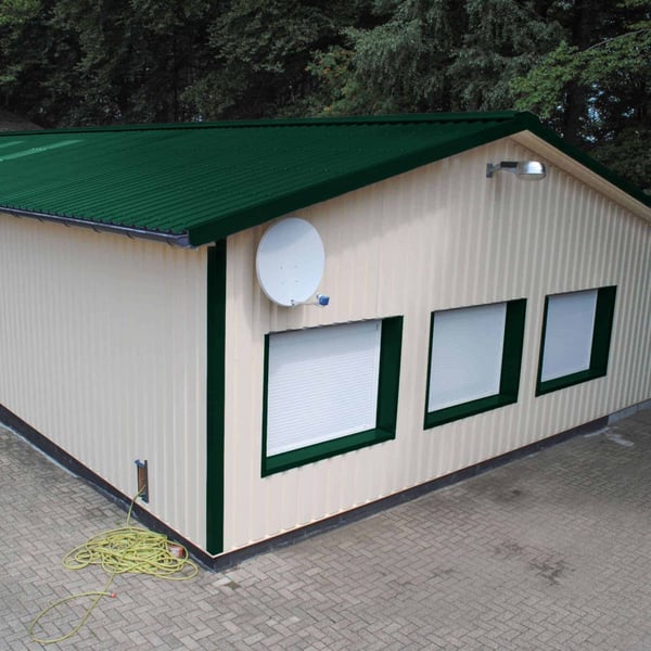 Damwandplaat 35/207 Mosgroen als dak op een gebouw met lichte muren, toepassingsvoorbeeld