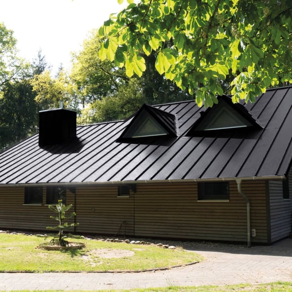 Felsplaat 33/500-LE Gitzwart op een woonhuisdak met dakramen en schoorsteen
