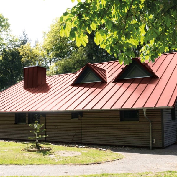 Staande felsplaat 33/500-LE, Roodbruin (RAL 8012), op een dak met dakkapellen en schoorsteen