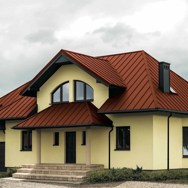 Staande felsplaat PD-510-S trapezium terracotta op een dak met dakkapellen en schoorsteen