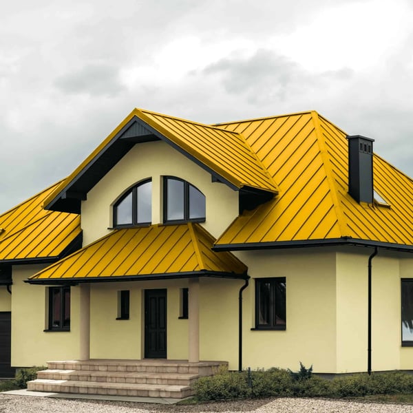 Huis met staande felsplaat PD-510-S damwand Koolzaadgeel en donkere accenten