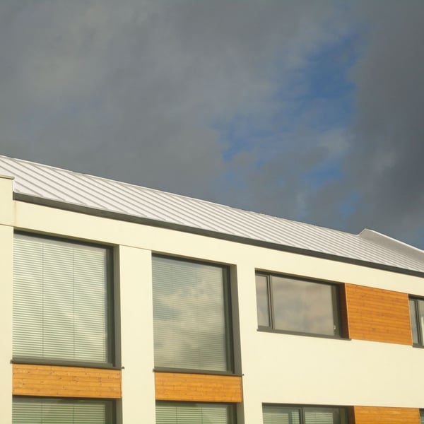 Staande felsplaat PD-510-S trapezium, zuiverwit, op een modern gebouw met grote ramen