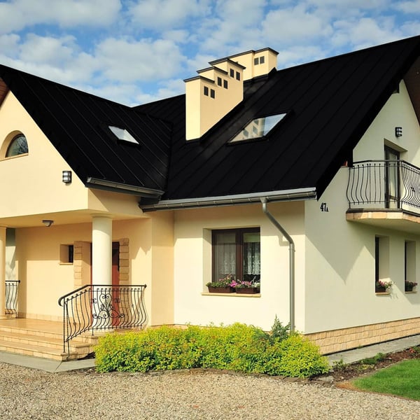 Felsplaat PD-510-S Gitzwart RAL 9005 op een dak van een huis met dakkapellen en schoorstenen
