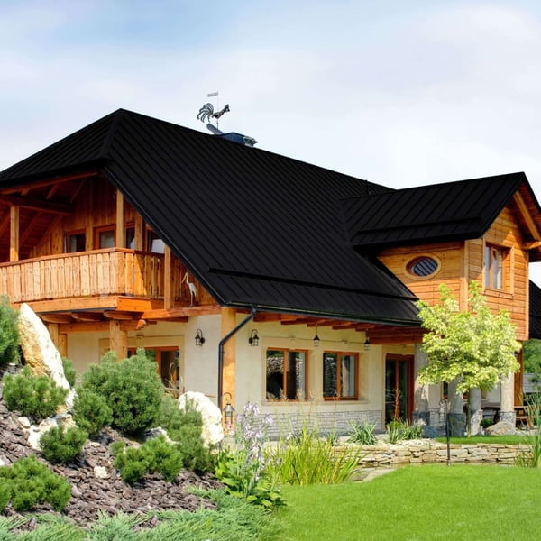 Felsplaat PD-510-S Gitzwart RAL 9005 op een dak van een huis met houten elementen en dakversiering