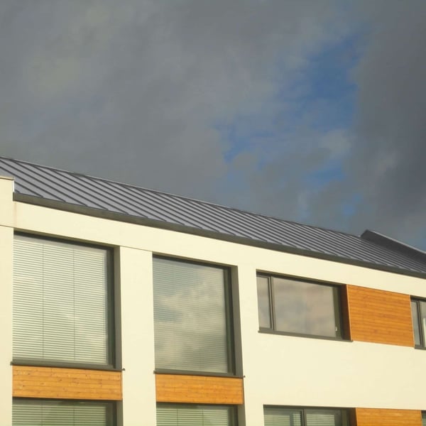 Modern gebouw met felsdakpan PD-510-S Zilver-Metallic dak onder bewolkte hemel