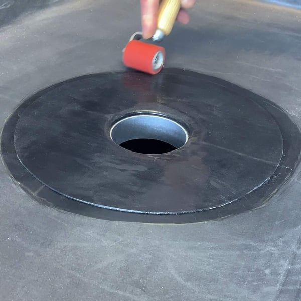 Hand rolt met een aandrukroller de zwarte EPDM garantie-gully stevig op de dakbaan