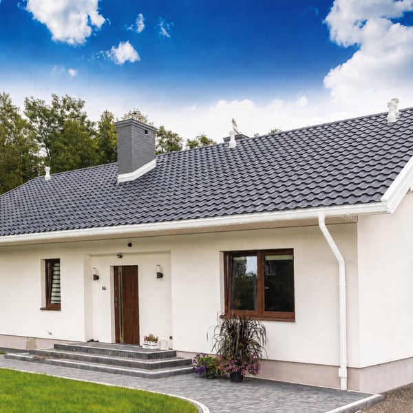 Witte (RAL 9010) Niagara dakgootsysteem met rinnenuitloop aan een huis met donker dak