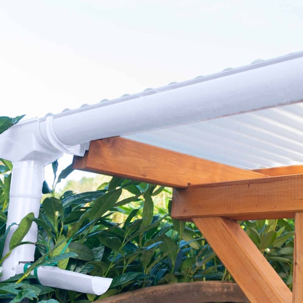 Witte PVC dakgoot met regenpijp en console dakgootbeugels aan een houten constructie