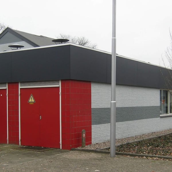 Gebouw met donkergrijs HPL platen 6 mm als dakrandbekleding boven rode en grijze bakstenen muren