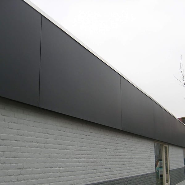 Dakrandbekleding van donkergrijs HPL platen 6 mm aan een gebouw met witte bakstenen muur