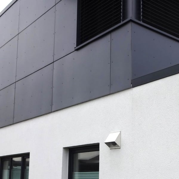 Gevelbekleding met donkere HPL platen op een gebouw, onderste gedeelte wit gepleisterd