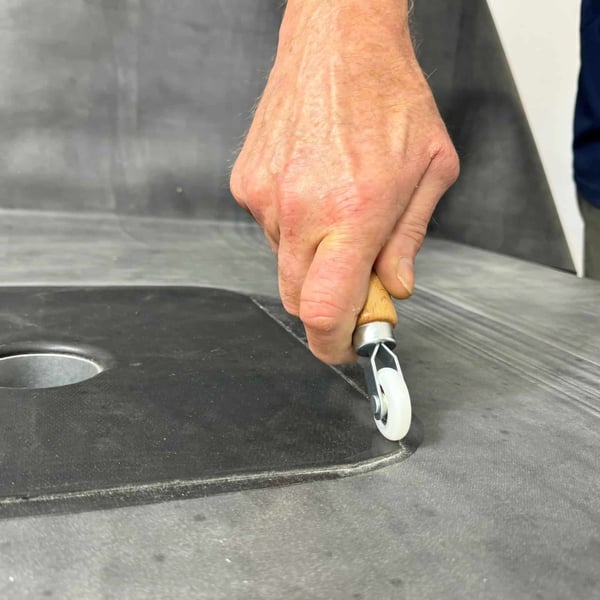 Hand leidt de metalen hoekroller met wit nylon wiel op donkere dakbedekking