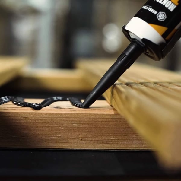 Montagelijm Turbo zwart wordt op een houten constructie aangebracht, detail van de lijmrups