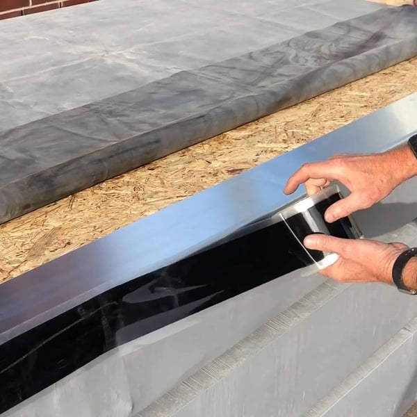 Montage van de zwarte EPDM naadband 0,75 mm op een dakbaan door twee handen