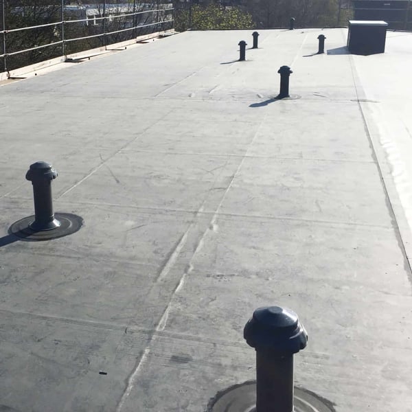 Meerdere zwarte EPDM buismanschetten op een plat dak met ontluchtingsbuizen