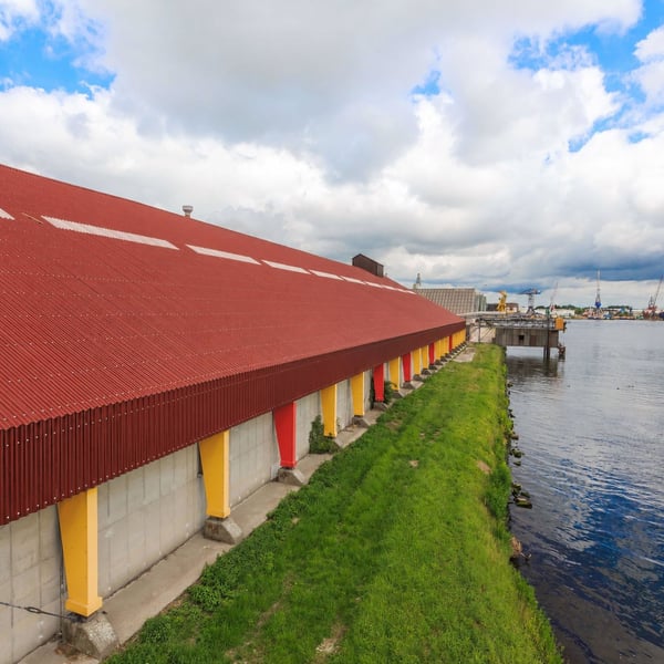 Lange hal met terracotta golfplaten dak langs een waterweg