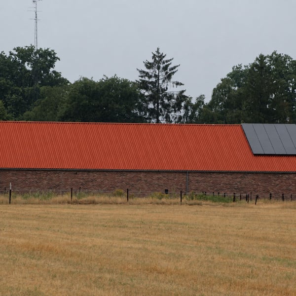 Groot gebouw met terracotta golfplaten dak en zonnepanelen