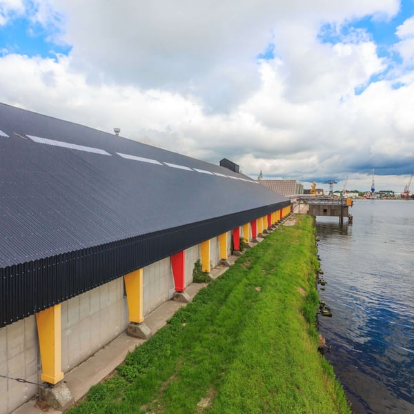 Lange bedrijfshal met donkergrijze golfplaten van Stabipol langs het water, verlegd