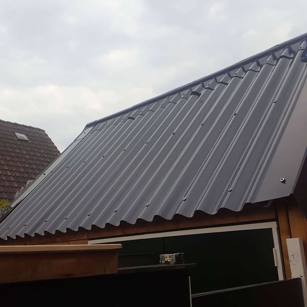 Donkergrijze golfplaten van Stabipol op een schuin dak, gemonteerd met schroeven