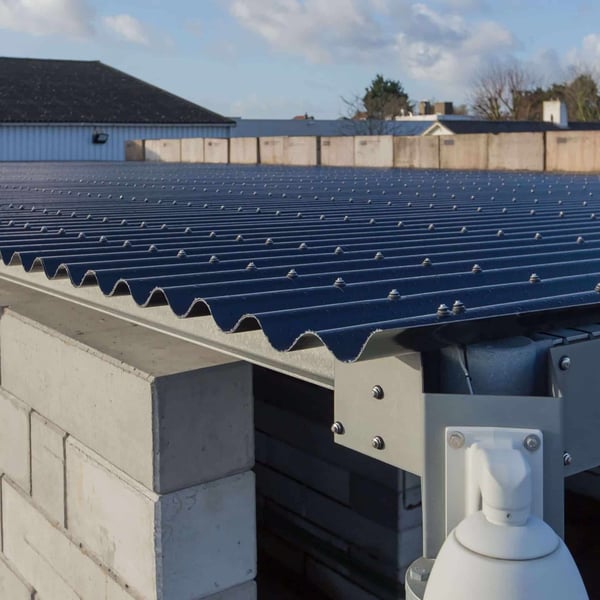 Detail van donkergrijze golfplaten op een betonnen constructie, verlegd