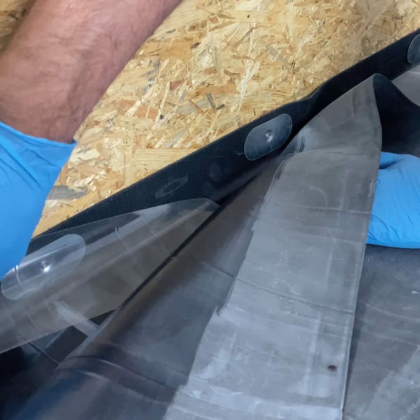 Montage randfixatiestrip EPDM zwart, hand met handschoen bevestigt strip aan hout