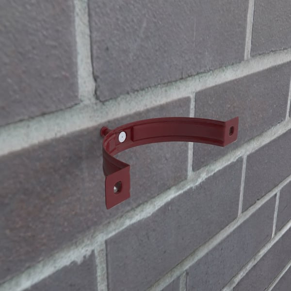 Kersrode valbuisklem van staal gemonteerd op een bakstenen muur, zonder valbuis