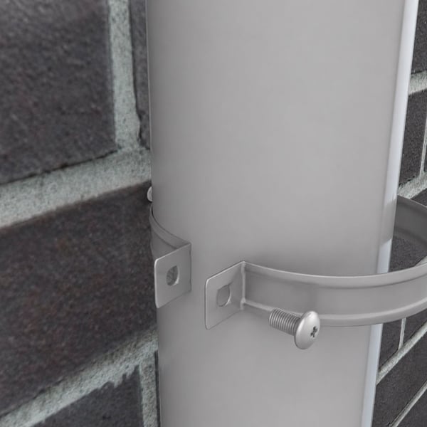 Detail van een grijs aluminiumkleurige (RAL9007) valbuis in een valbuisklem aan een bakstenen muur
