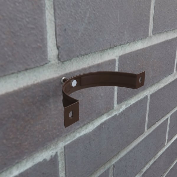 Chocoladebruine regenpijpbeugel van staal, gemonteerd op een bakstenen muur, detail van de bevestiging