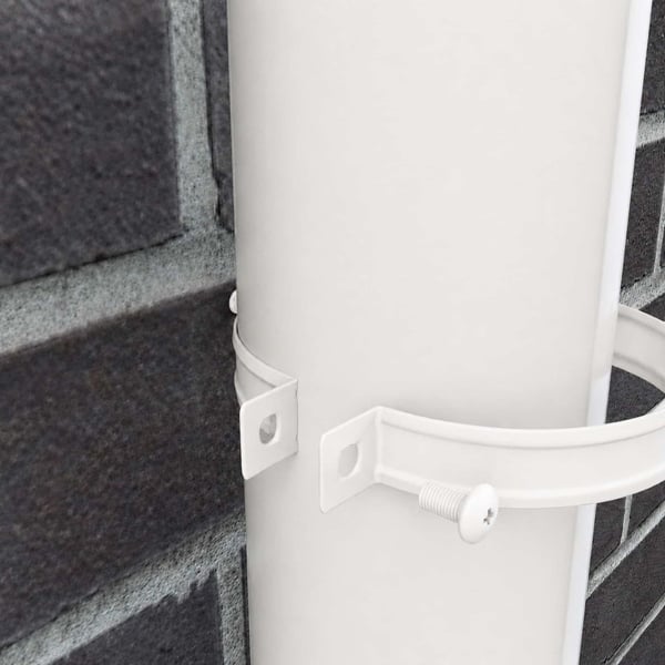 Detail van zuiverwitte (RAL 9010) regenpijpbeugel gemonteerd op een regenpijp aan een bakstenen muur