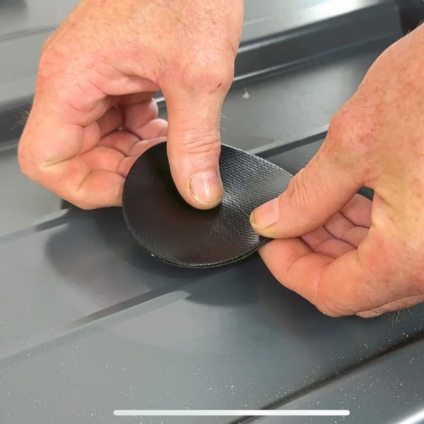 Handen plaatsen een zwarte EPDM schroef reparatiepleister op een profielplaat