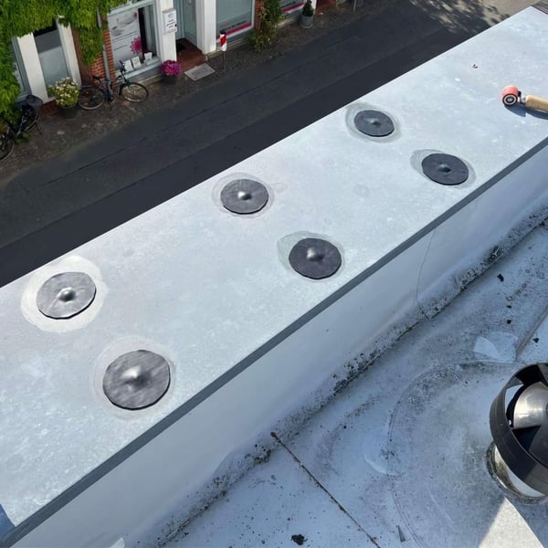Meerdere zwarte EPDM schroef reparatiepleisters op een licht plat dak gelegd
