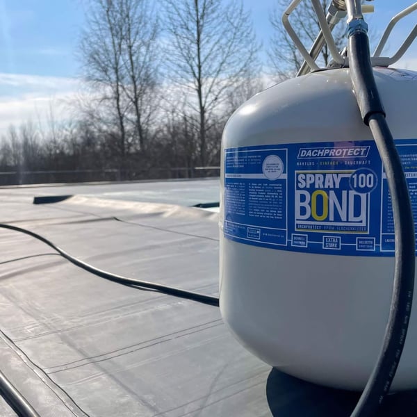 Slang voor spuitlans, zwarte slang aangesloten op een DACHPROTECT Spray 100 BOND bus op een dak