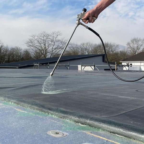 Spuitlans in gebruik op een plat dak, een hand houdt de lans vast