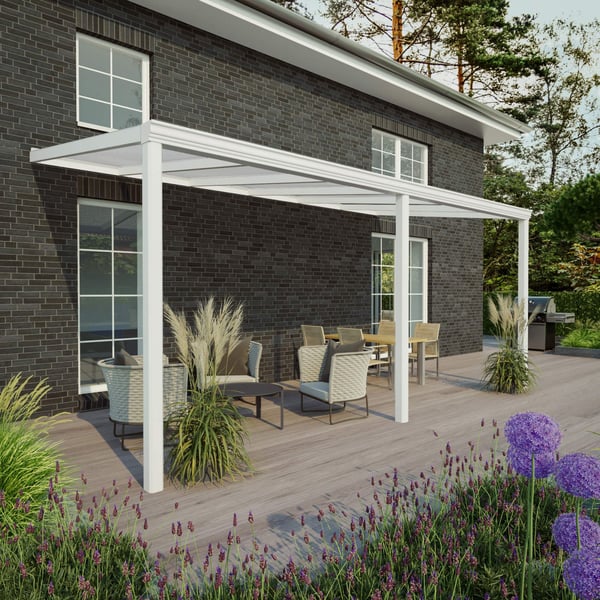 Terrasoverkapping wit, 16 mm, RAL 9016, aan een huis met donkere bakstenen muur, met zithoek op houten terras