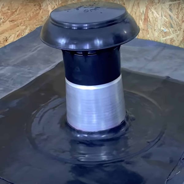 Platdak ontluchter van DACHPROTECT, zwart en zilver-metallic, gemonteerd op een dakbedekking