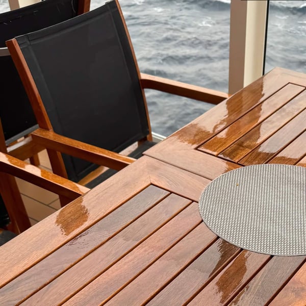 Vloeibaar kunststof transparant op een houten tafel buiten, water parelt van het oppervlak af