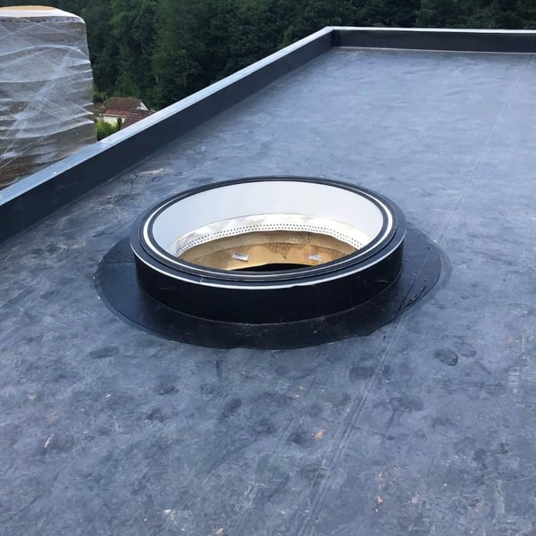 Plaatsing van het zwarte DACHPROTECT vorm- en afdekband van EPDM rond een ronde dakopening
