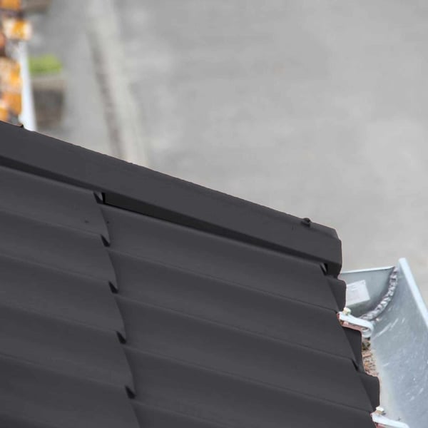 Detail van de windveer Gitzwart RAL 9005 aan de dakrand met dakgoot