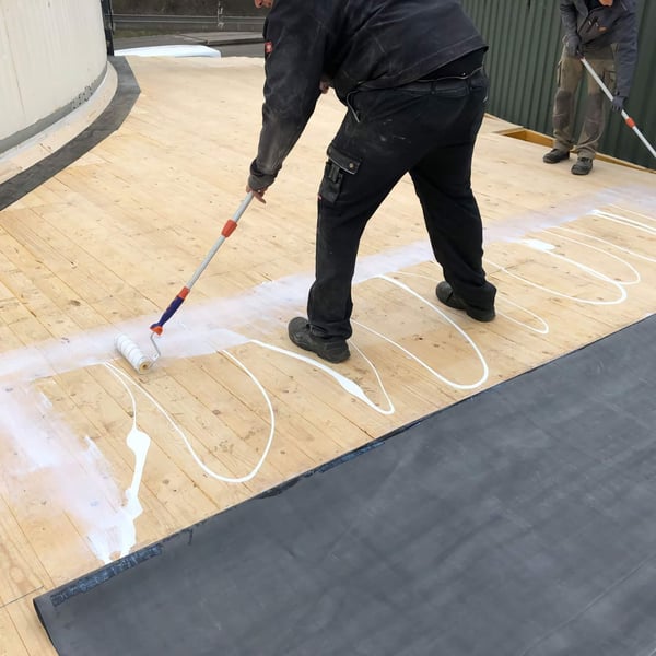Oppervlaktelijm voor EPDM met de verfroller aanbrengen op het houten dakbeschot