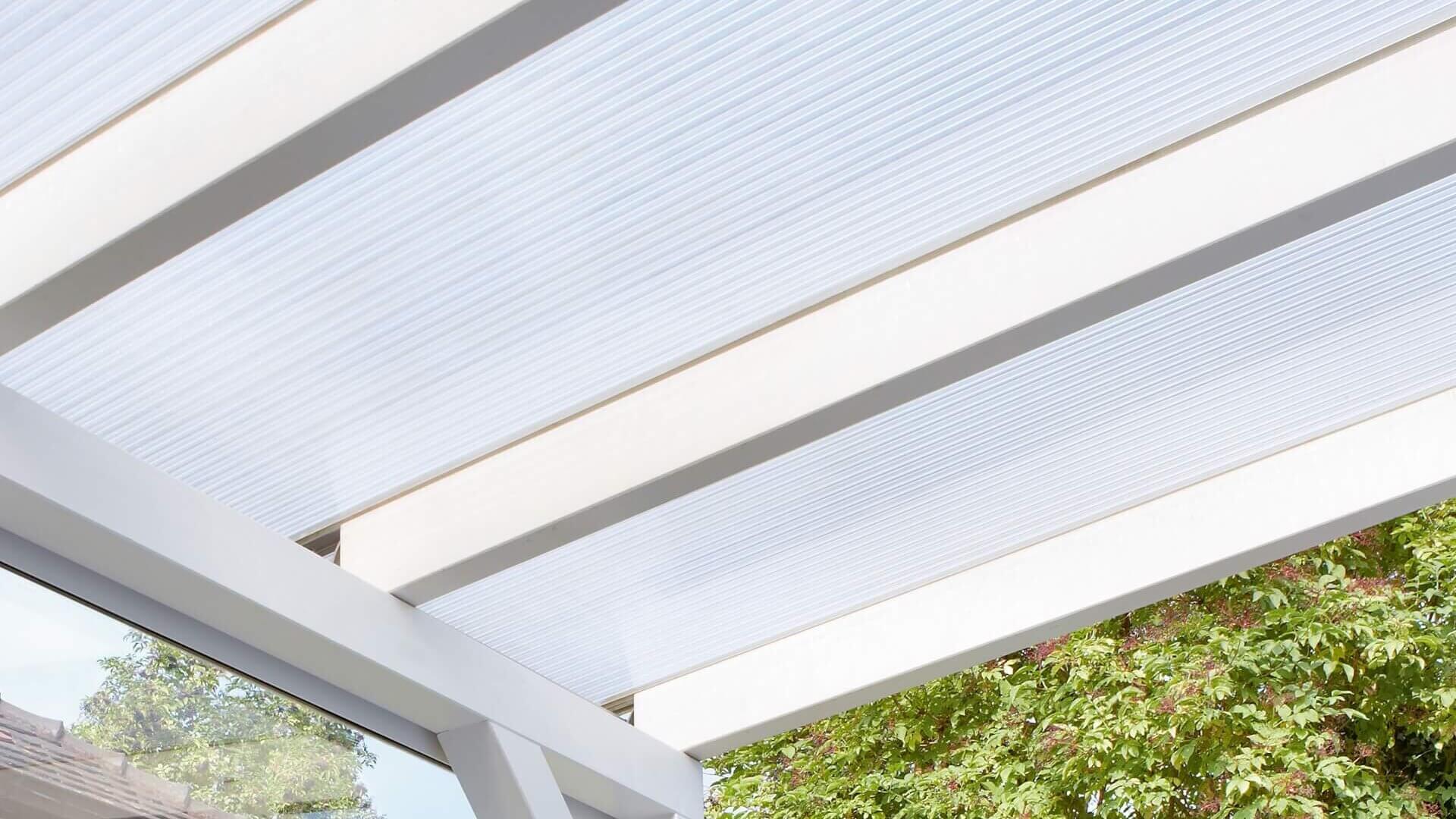 De foto toont een terrasoverkapping met kanaalplaten.
De onderconstructie is wit, de kanaalplaten zijn transparant.