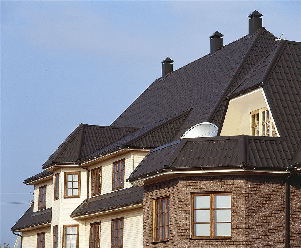 Grote bakstenen woning met dakpanplaat in een donkere kleur.