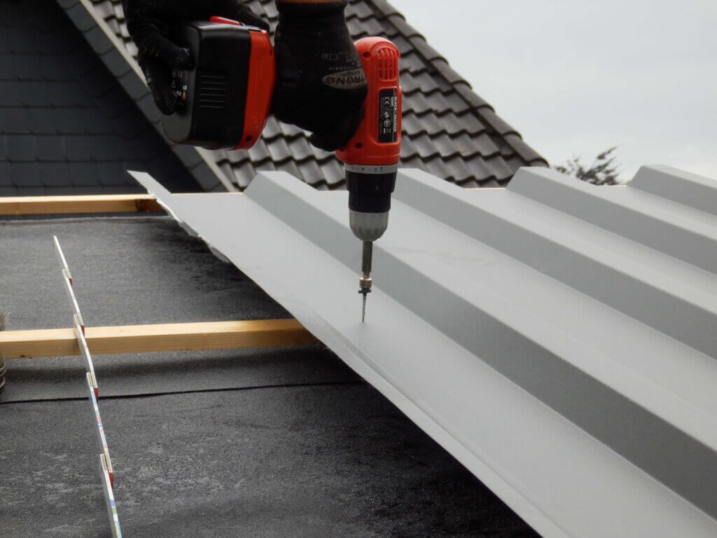 Montage van een lichtgrijze damwandplaat met behulp van een boormachine.