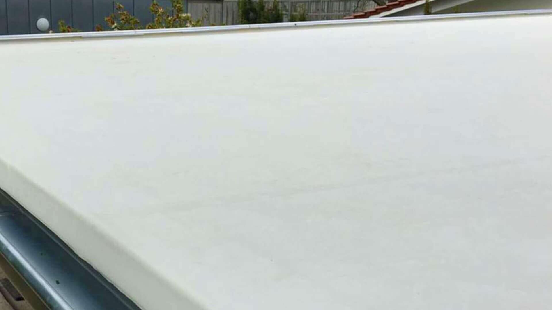Plat dak met netjes gelegde witte EPDM-dakbedekking, gecombineerd met een stevige regengoot voor waterafvoer.